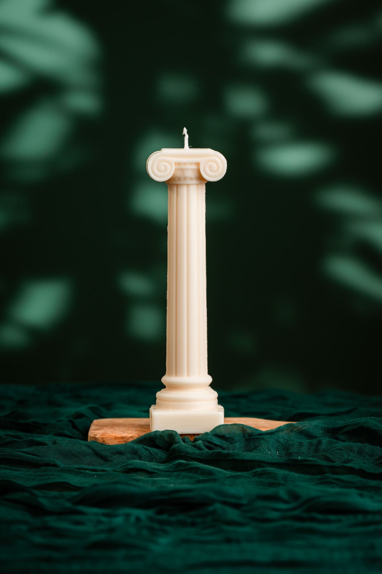 Decorative column candle on a dark green fabric background