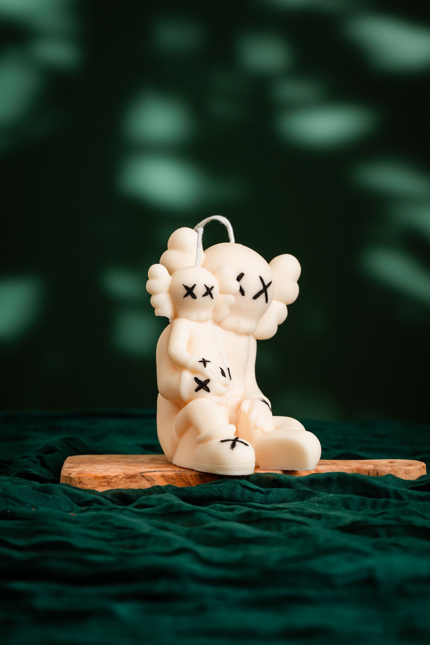 White plush toy with black markings on a wooden platform against a dark green background