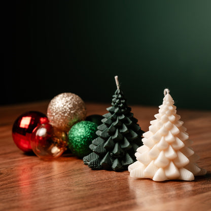 A white 3D Christmas tree-shaped candle, along with colorful Christmas ornaments, on a wooden surface.