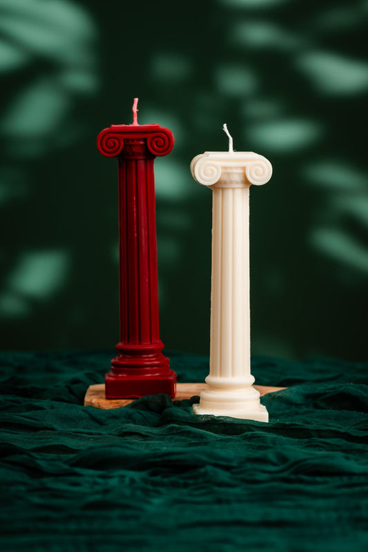 Two candle columns, one red and one white, on a dark green fabric background.