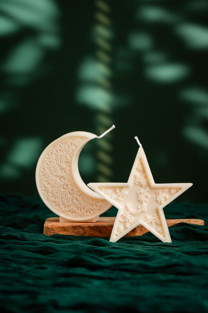 Decorative candle holders shaped like a moon and a star on a dark green fabric background