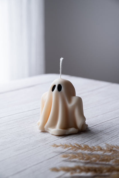 Ghost-shaped candle on a wooden surface with a blurred background