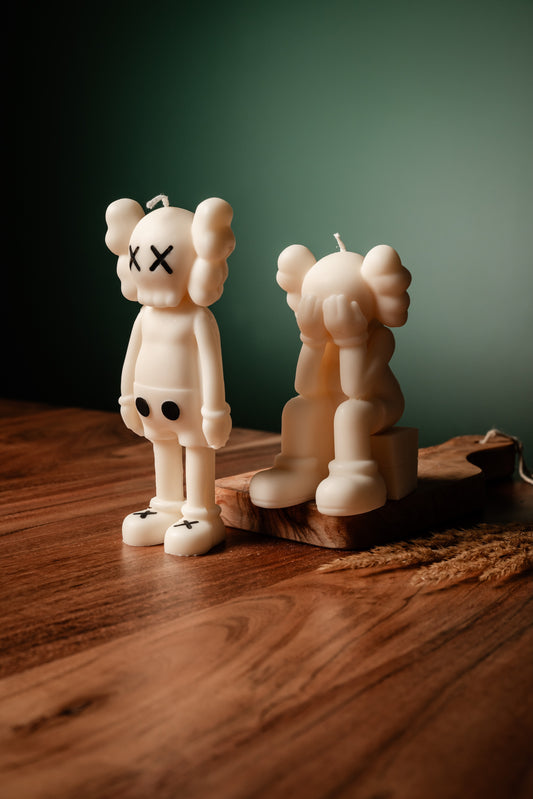 Two white bear-shaped candles on a wooden surface with a dark green background