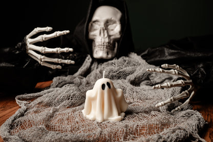 Skeleton figure with a candle shaped like a ghost on a dark background