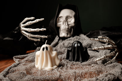 Skeleton figure with a candle shaped like a ghost on a dark background