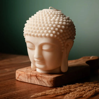 Buddha head soy wax candle on a wooden base with a green background