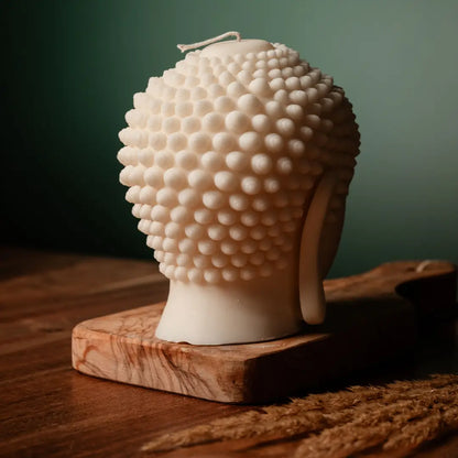 Buddha head sculpture on a wooden base with a dark green background